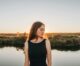 a woman standing in front of a body of water